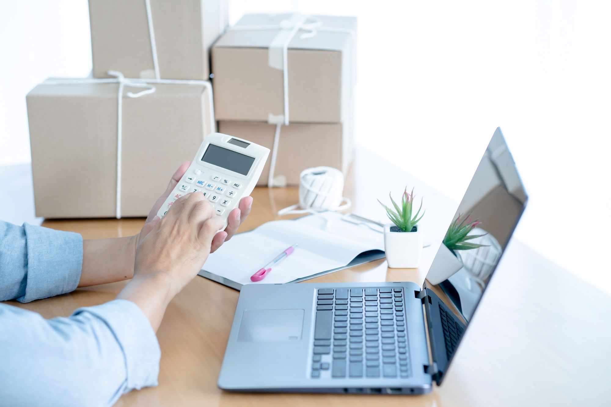 A male seller's hand calculating the total amount of online orders to be shipped 