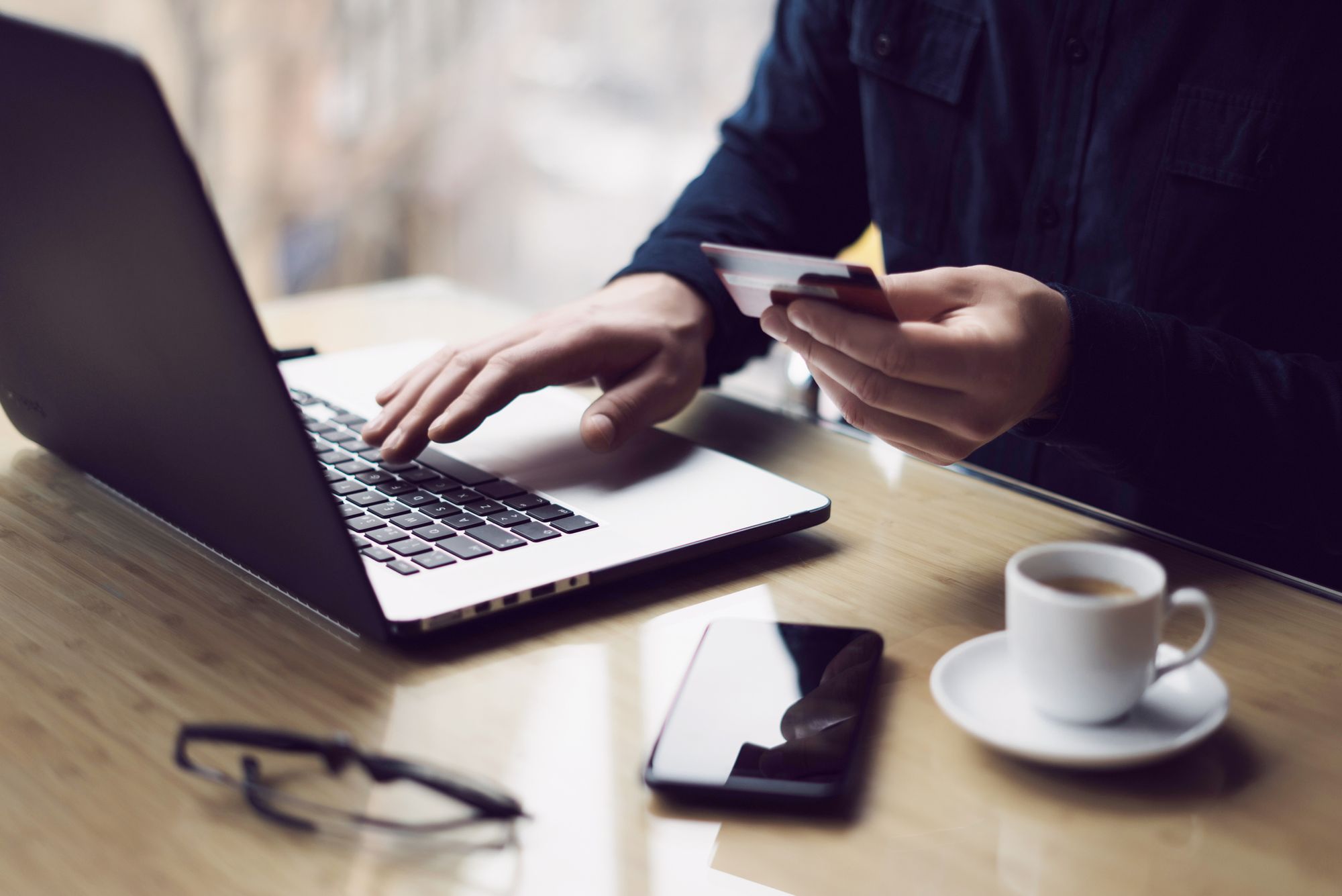 A male paying online with a credit card using a laptop