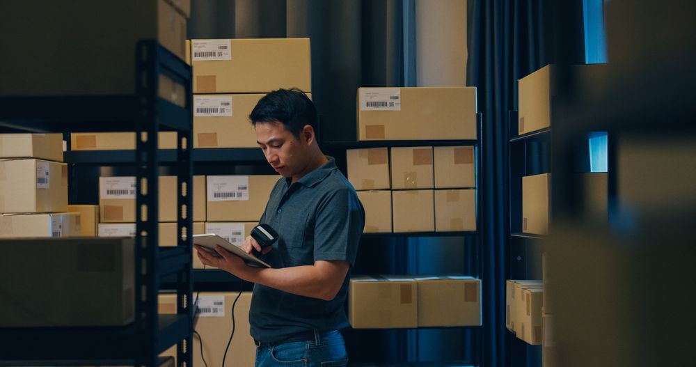 A male conducting inventory count in the warehouse using a barcode scanner