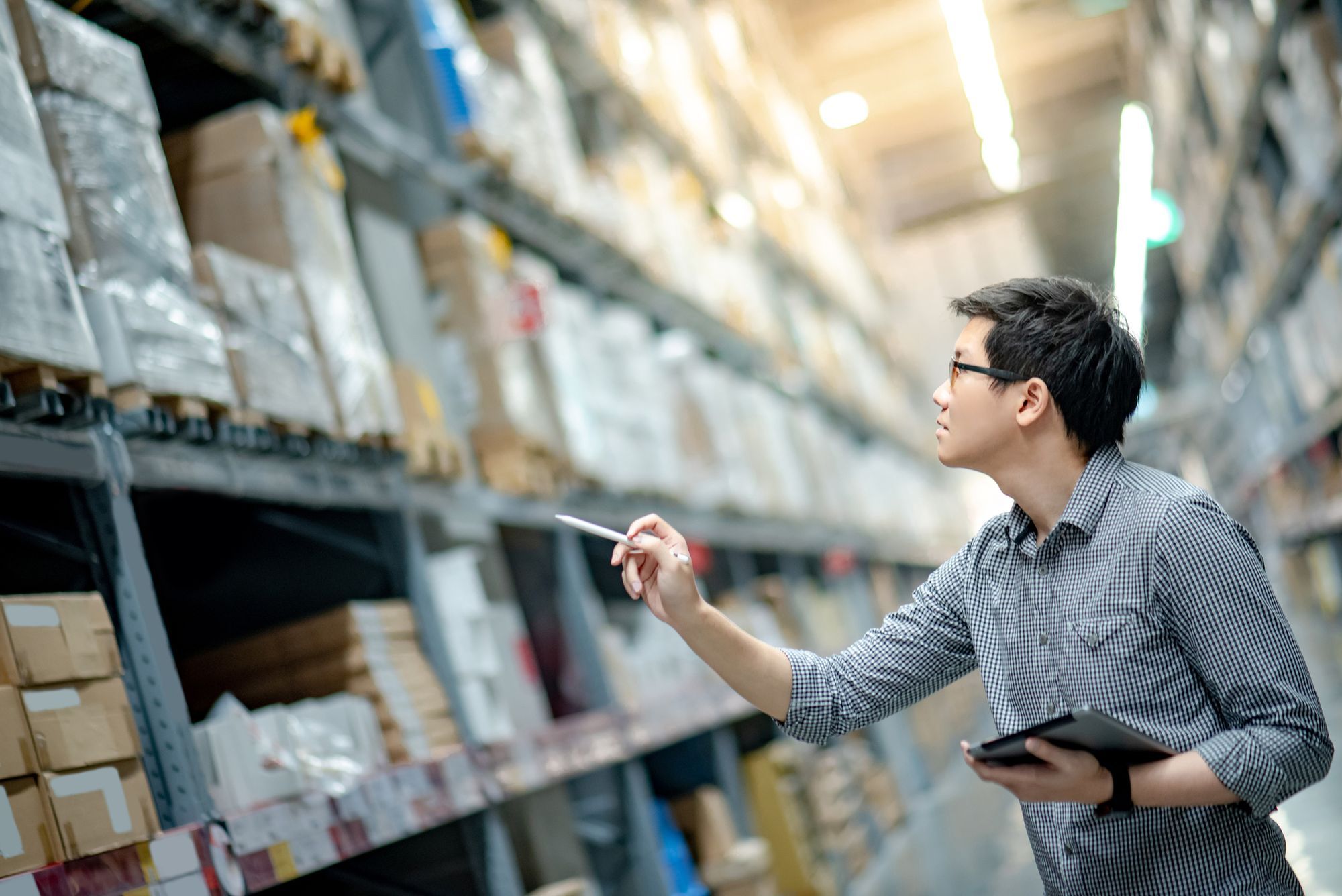 A man with a tablet PC looking at his inventory in a warehouse.