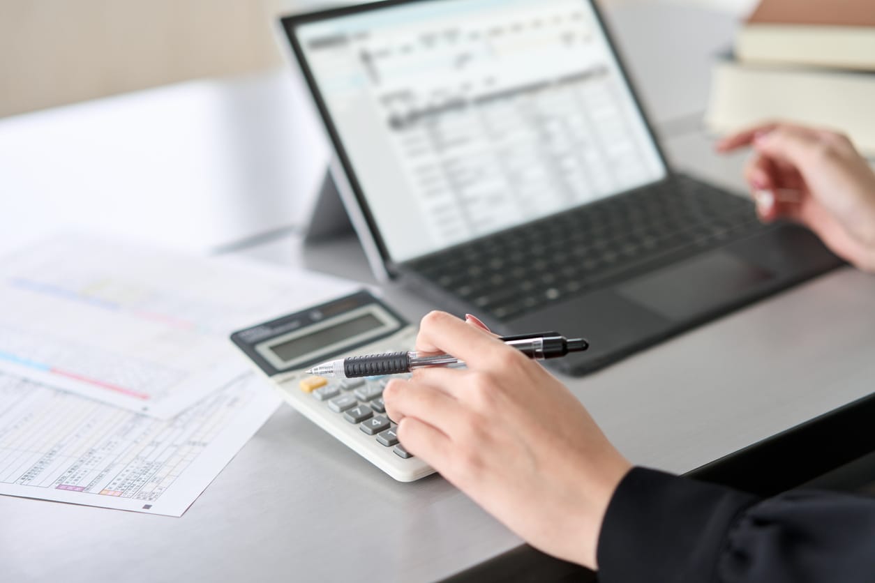 Asian woman entering journal entries in accounting software.