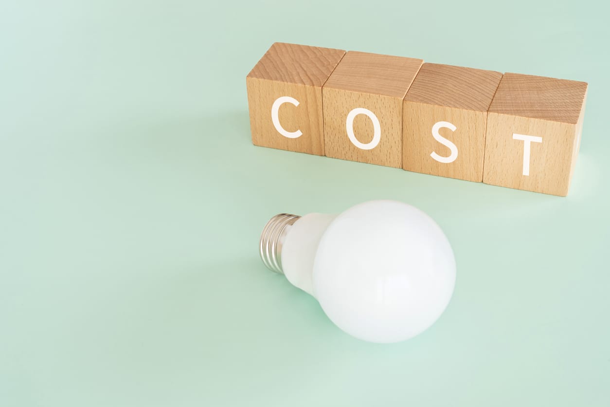 Wooden blocks with "COST" text of concept and a lightbulb.