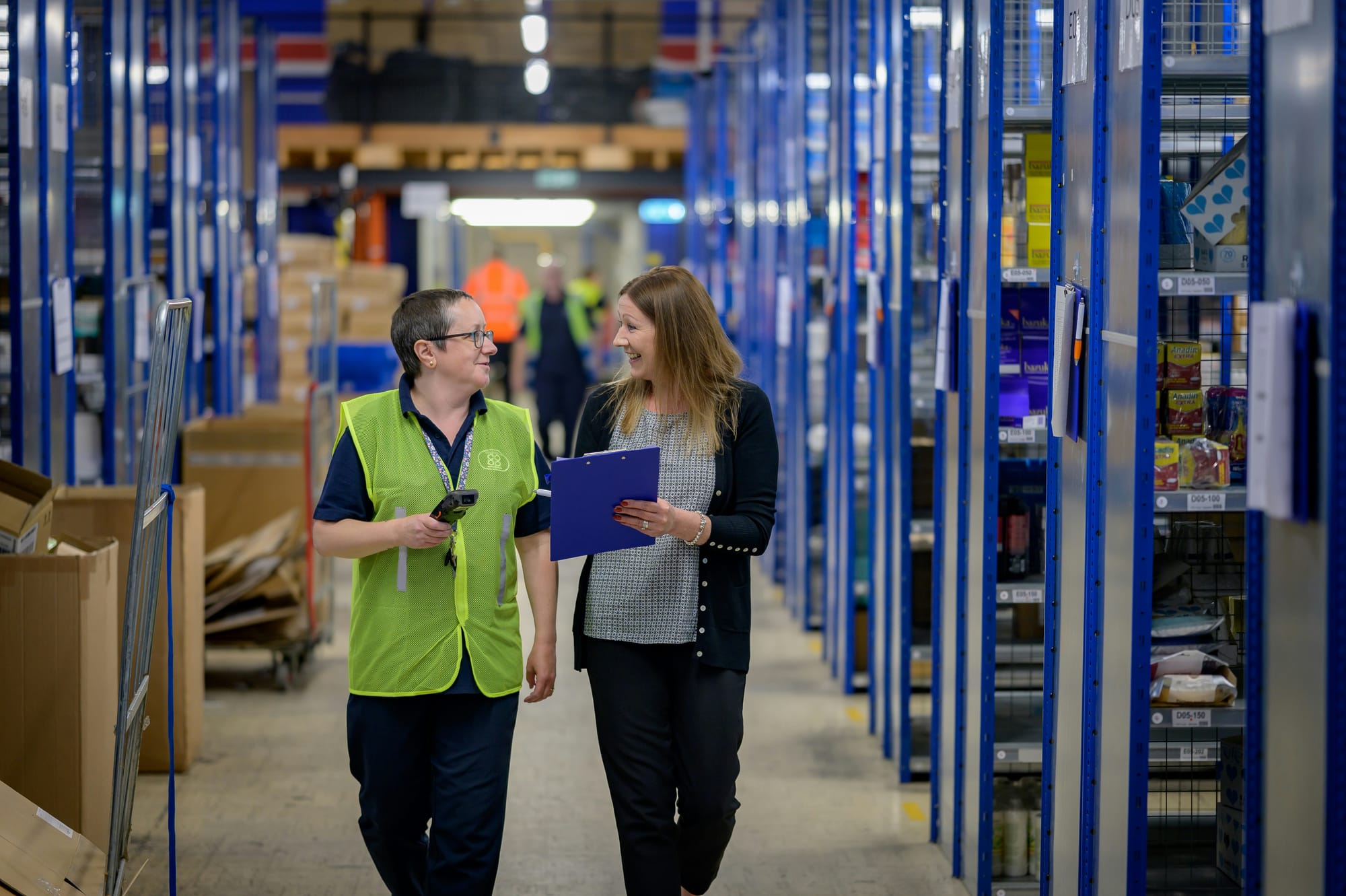 Inside a large warehouse, workers are managing inventory together