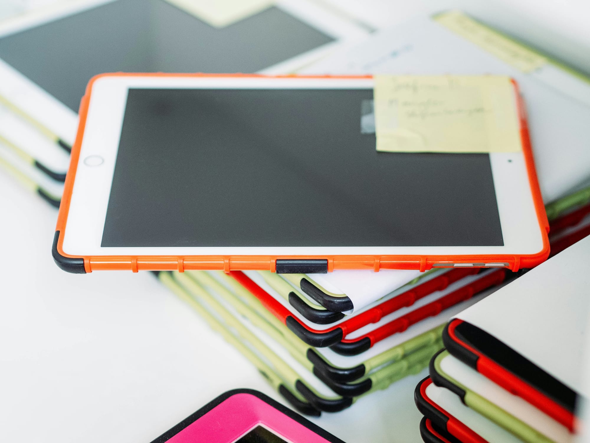 A tack of tablet devices on a white desk