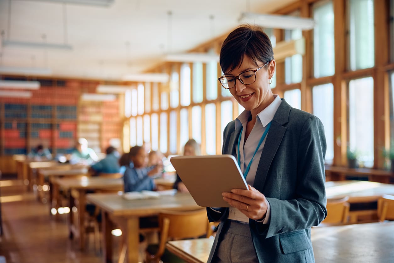 Female professor using touchpad tablet in classroom at high school