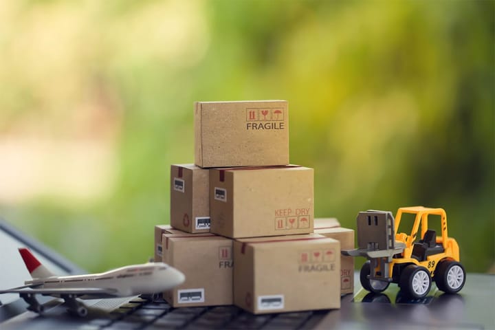 Fork-lift a truck moves a paper box on notebook keyboard in the natural green background. 